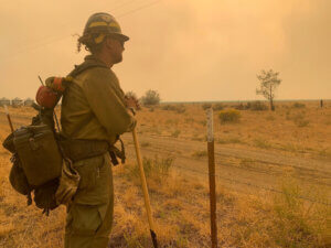 A firefighter looks out over a smoky landscape