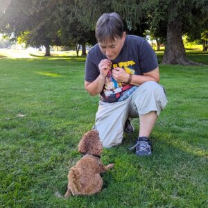 A trainer encourages a small dog to work for a treat.