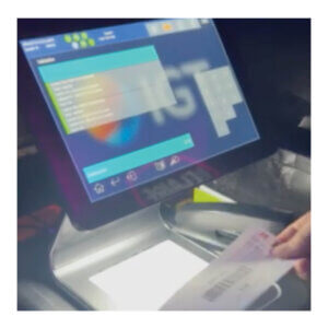 A soft-focus image of a Lottery iLink machine. A hand is holding a Video Lottery gameslip near the screen